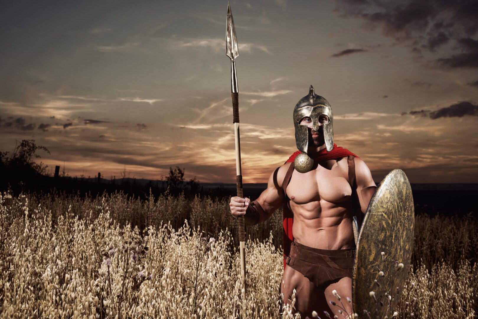 Front view of warrior in armor and helmet like antique roman going forward in attack. Soldier wearing in red cloak like spartan holding bronze sword and looking at camera. Dark sky and bad weather.