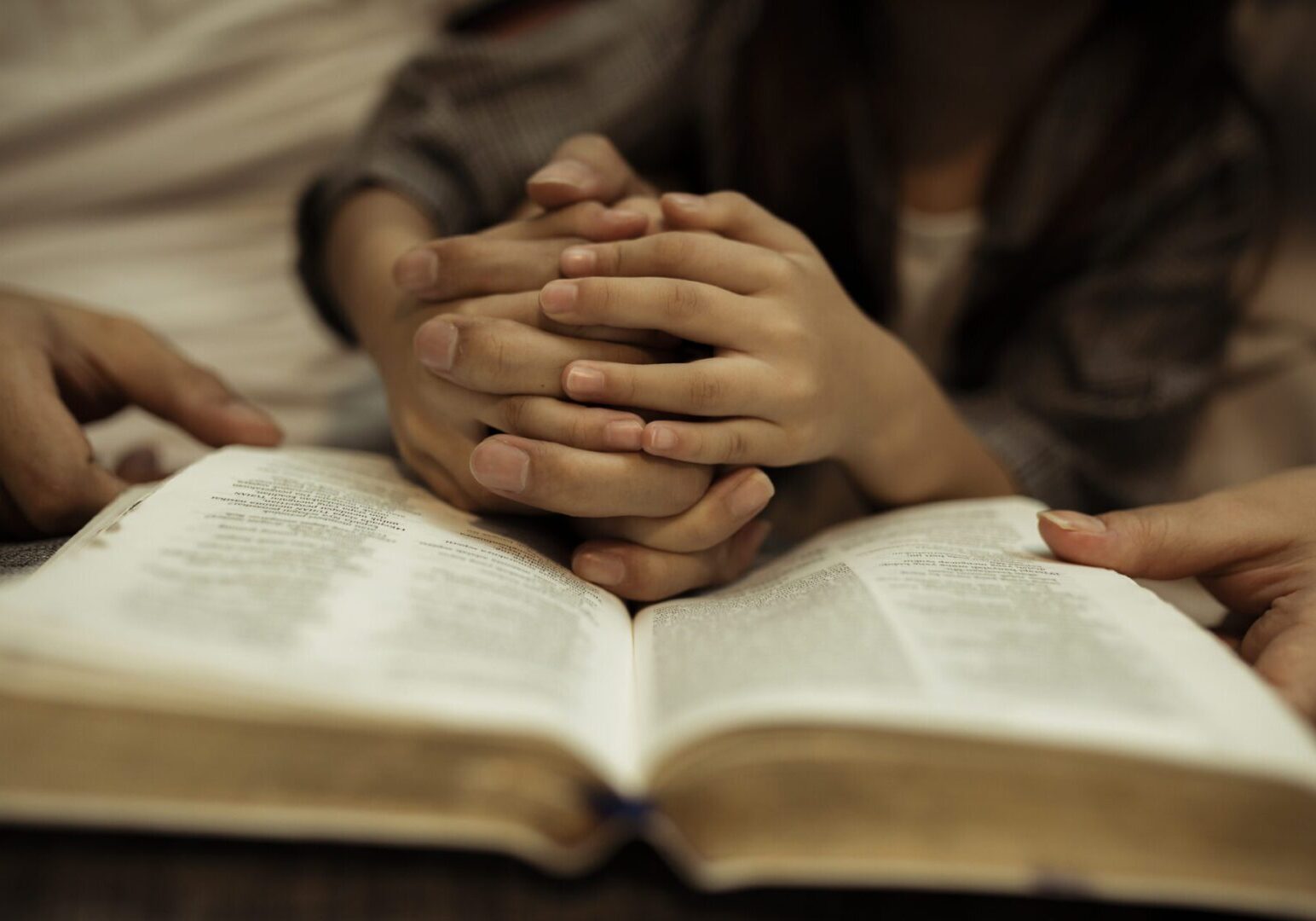a kid reading the holy bible with guide by parents